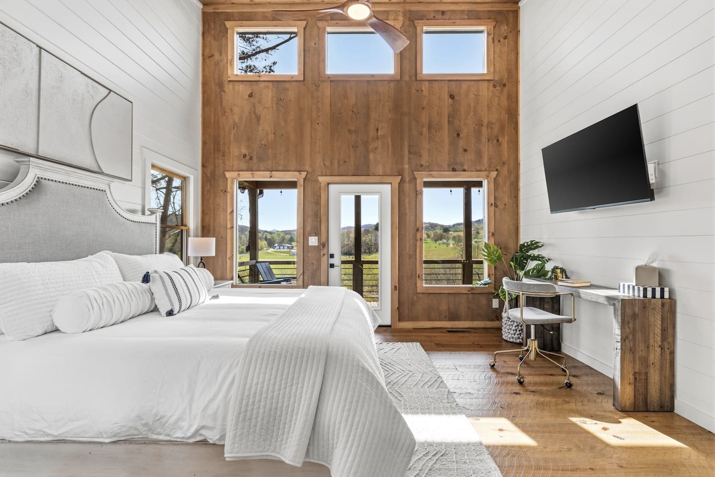 Wake up refreshed in this bright primary bedroom with a luxurious king Tempur-Pedic mattress. Soaring wood walls, large windows with beautiful pastoral views, ceiling fan, wall-mounted TV, and a cozy desk nook create the perfect peaceful retreat.