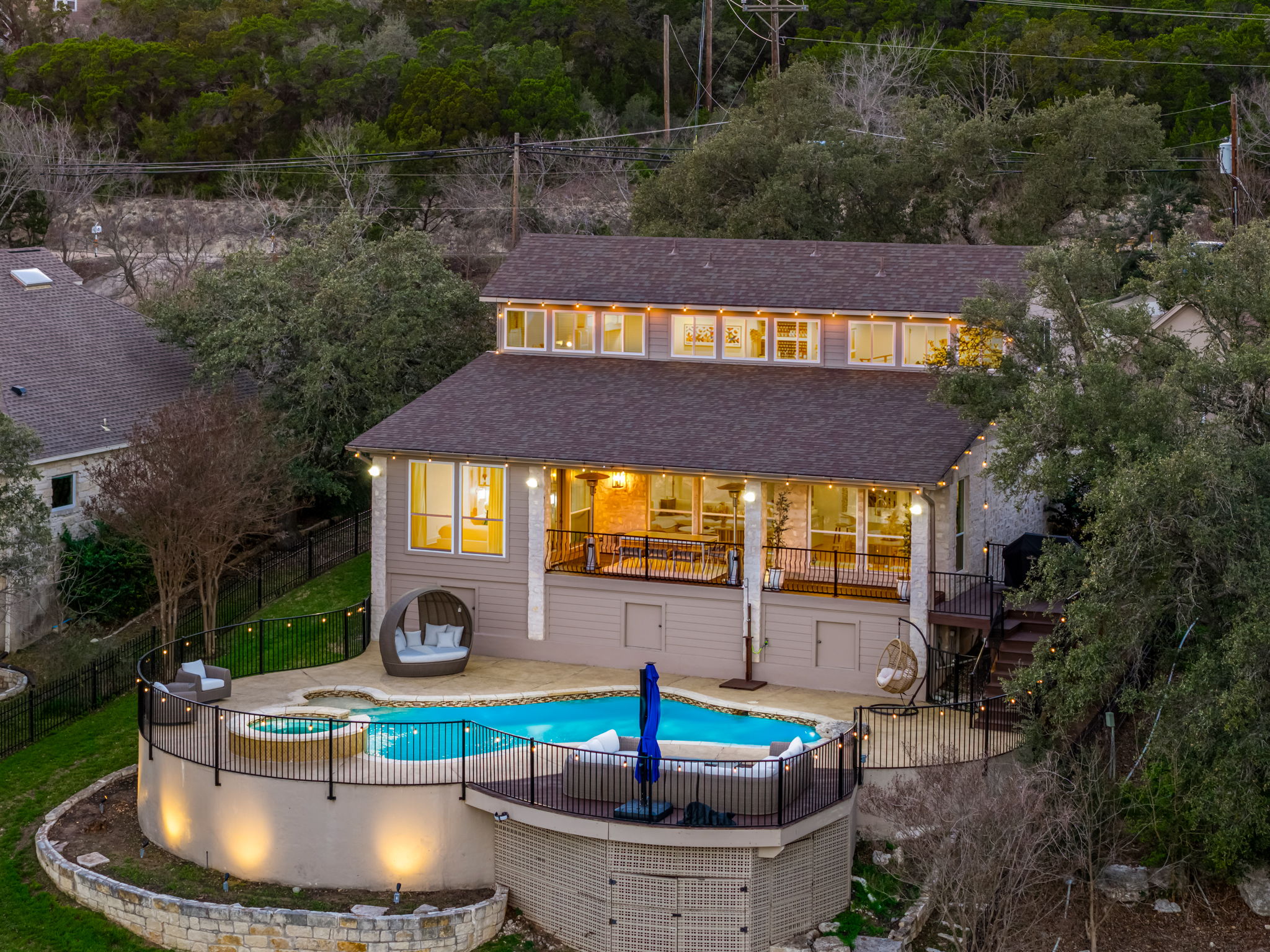 Beautiful evening view of the home with glowing backyard pool and spa.