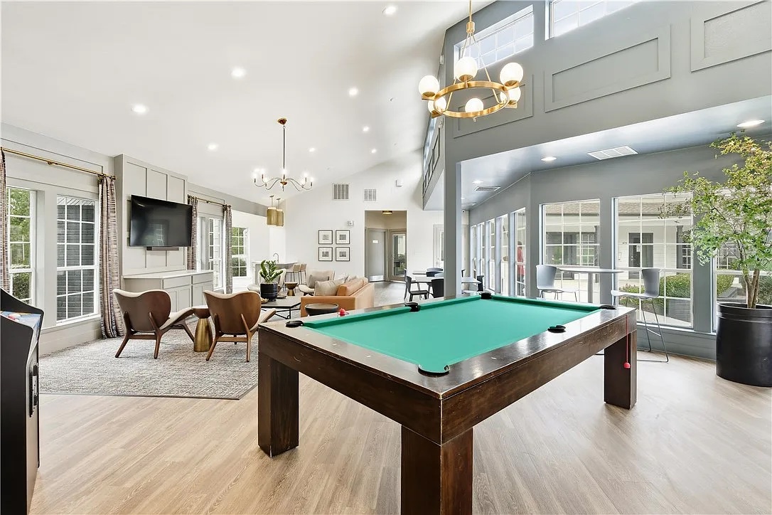 Sofas, a big screen, and a pool table under a two-story ceiling — the overflow living room you didn't pay for.