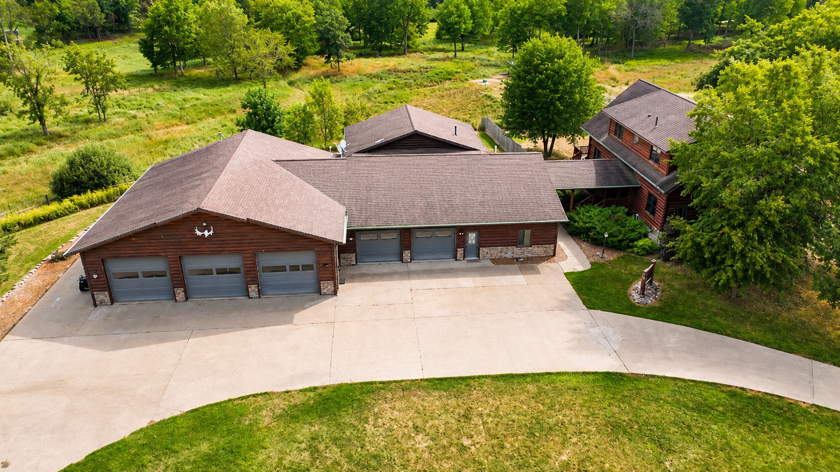 Aerial view of the property entrance, buildings, driveway, and parking area, showing the generous space available for larger groups traveling with multiple vehicles and outdoor gear.