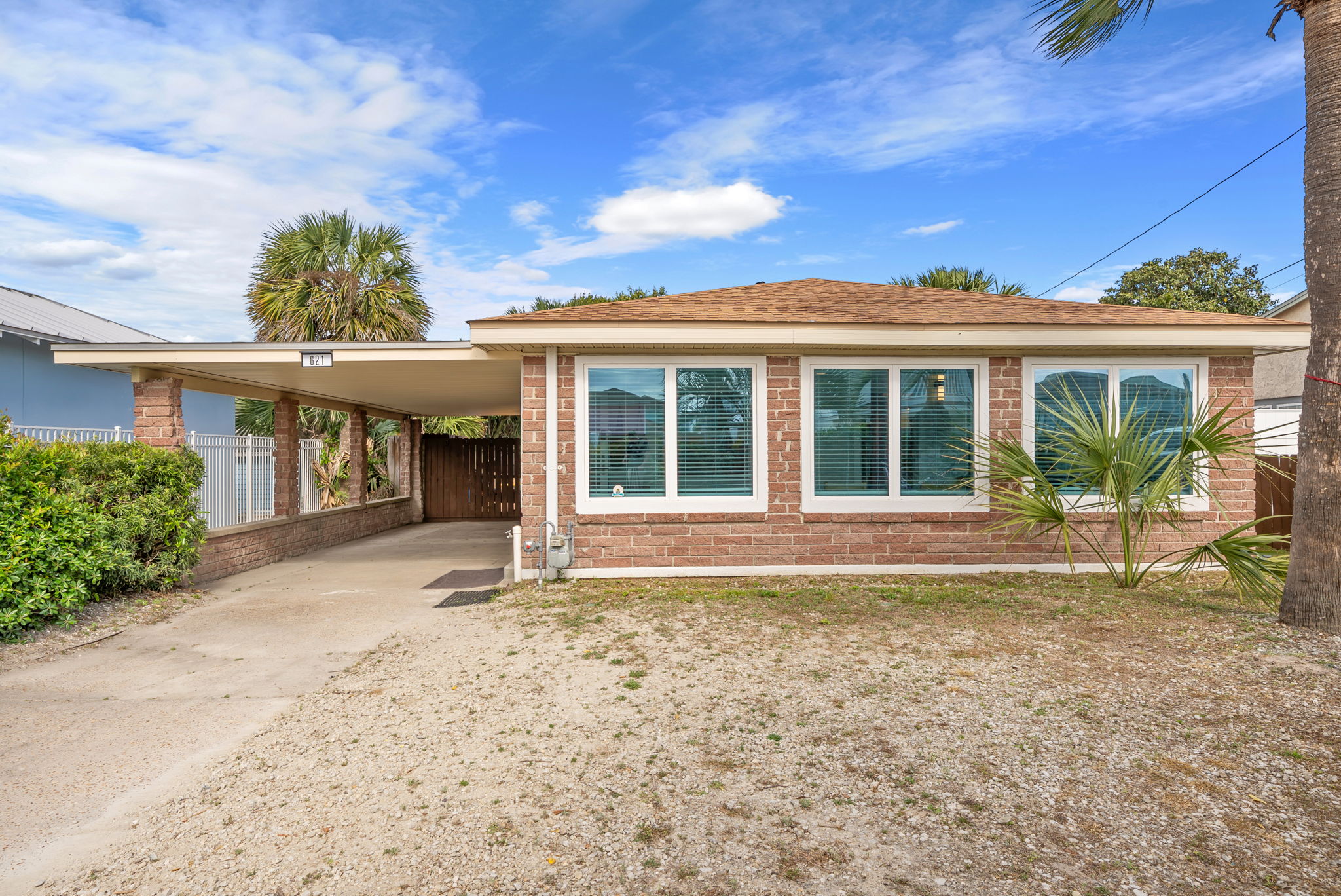 Pull right up to the covered carport of this brick ranch home.  Palm trees frame the entry, picture windows face the front, and the Gulf
is behind you.