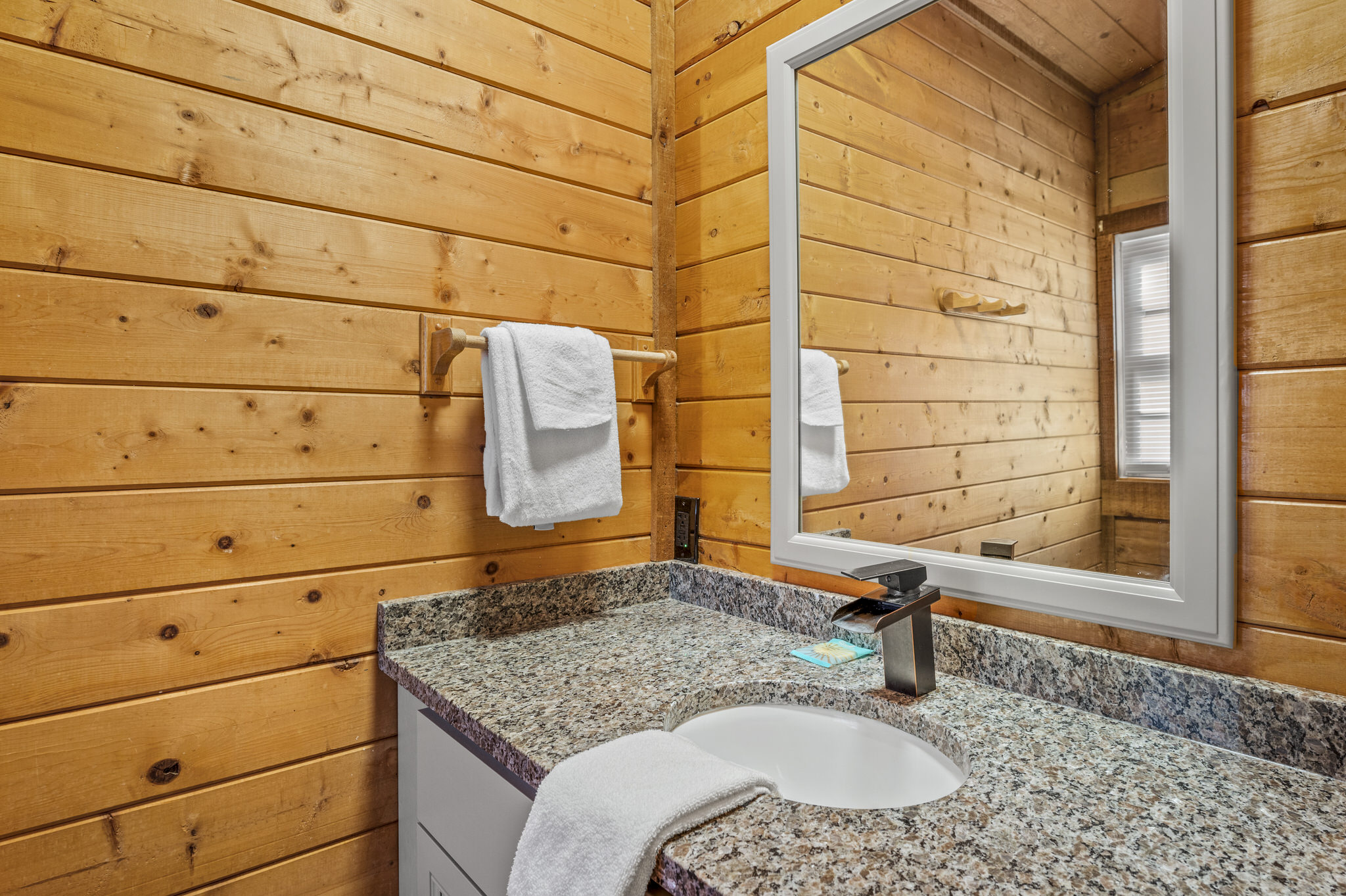Bright bathroom vanity with wood walls and fresh towels.