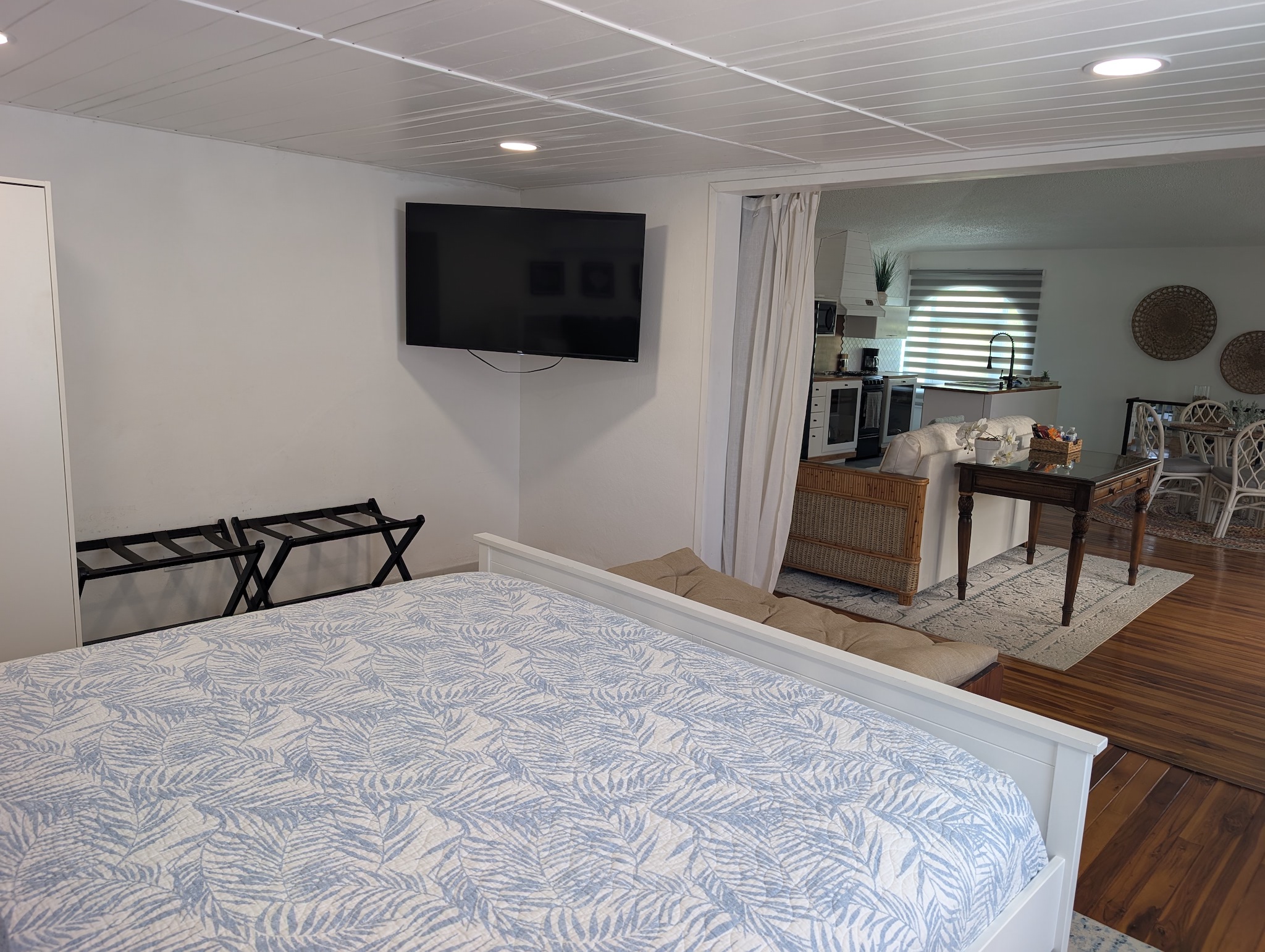 View from the upstairs king bed at Villa Coral looking past a large wall-mounted flat screen television into an adjacent open-concept second living room lounge and kitchenette area in Dorado, Puerto Rico.

