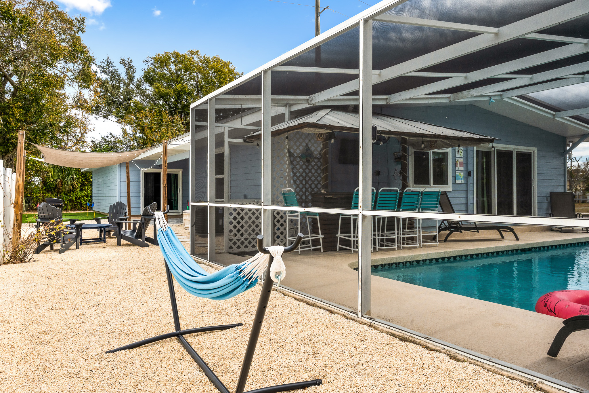 Backyard hammock with a relaxing view of the pool — the perfect spot to unwind and enjoy your favorite show on the outdoor Smart TV.