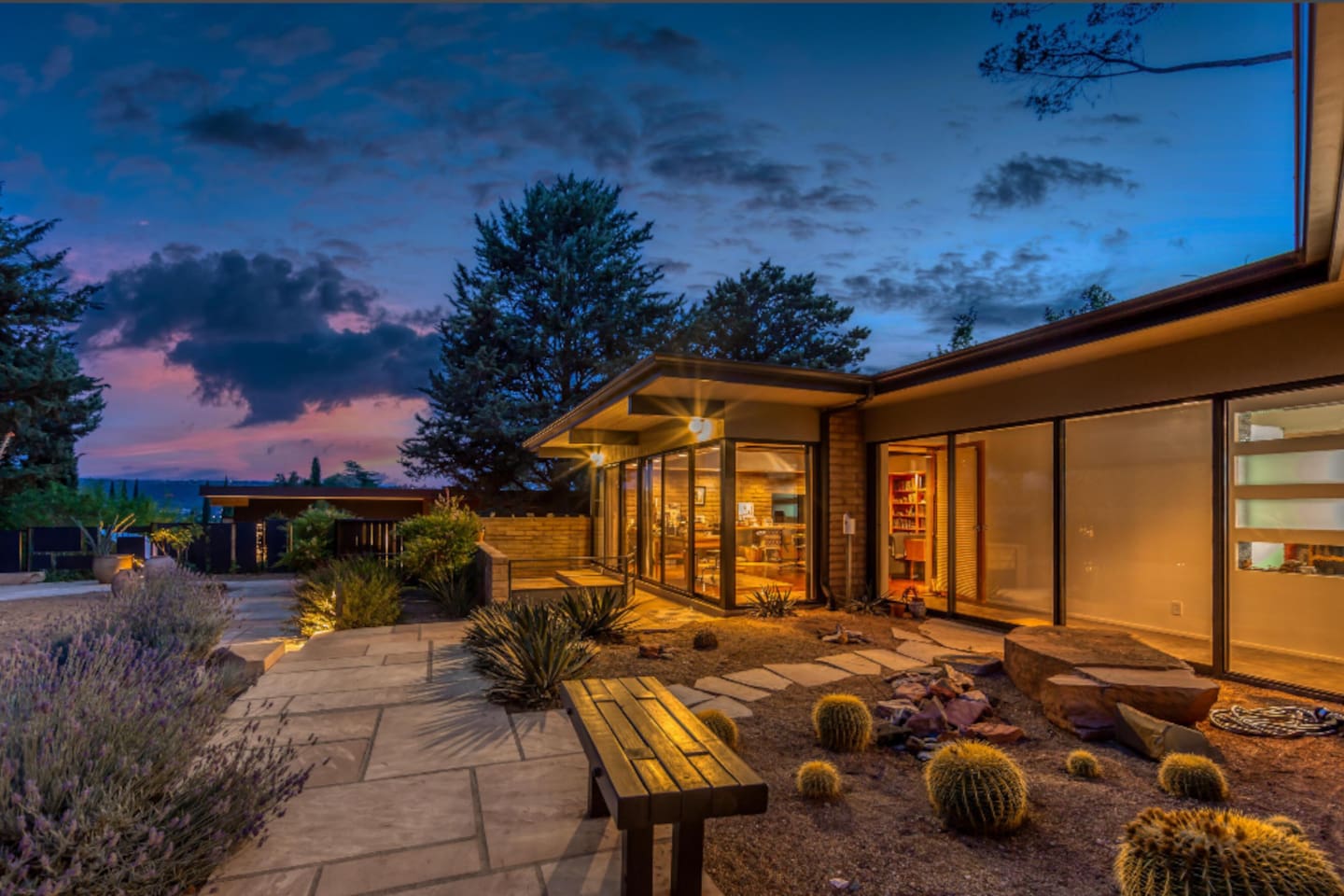 Breathtaking twilight views surround this architectural gem, where floor-to-ceiling glass and warm interior lighting create an inviting glow against Sedona’s vibrant sunset sky.