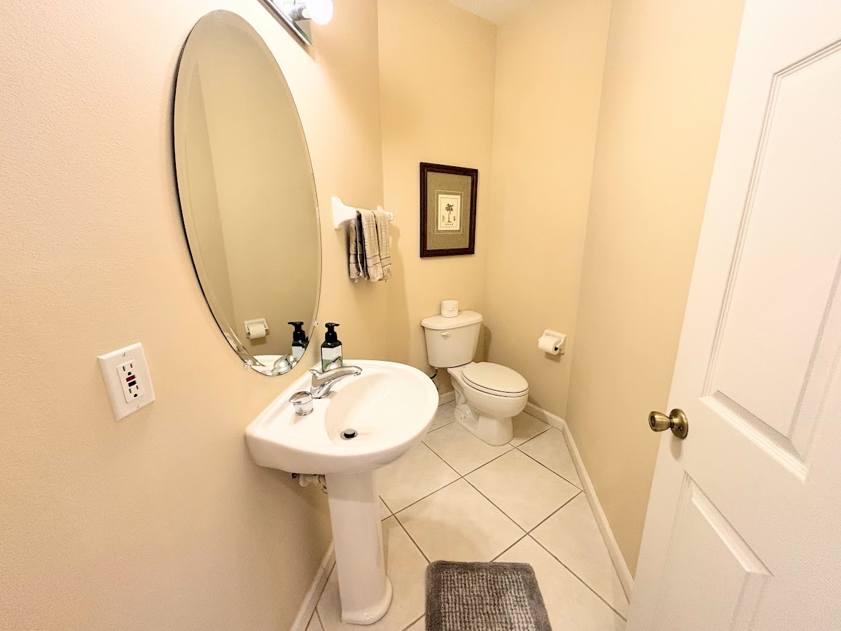 Convenient half bathroom with pedestal sink, tile flooring, and clean neutral finishes.