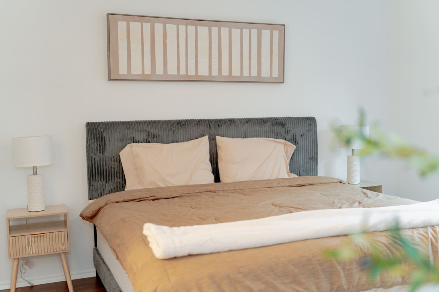 Bedroom view with upholstered bed and warm natural tones.
