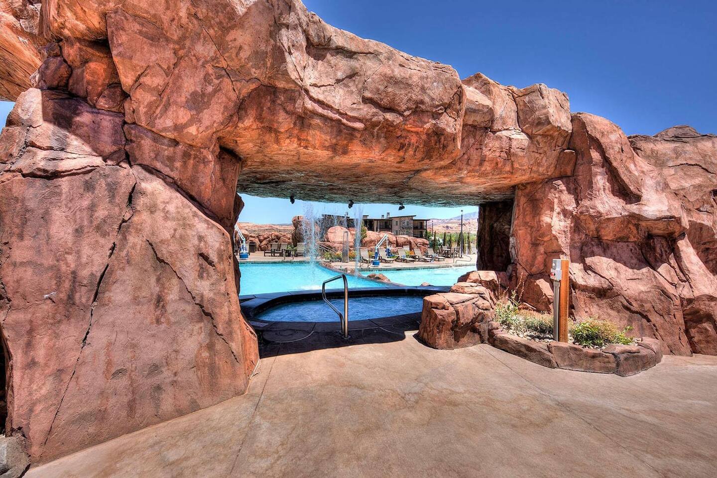 Poolside hot tub hidden under red rock grotto 