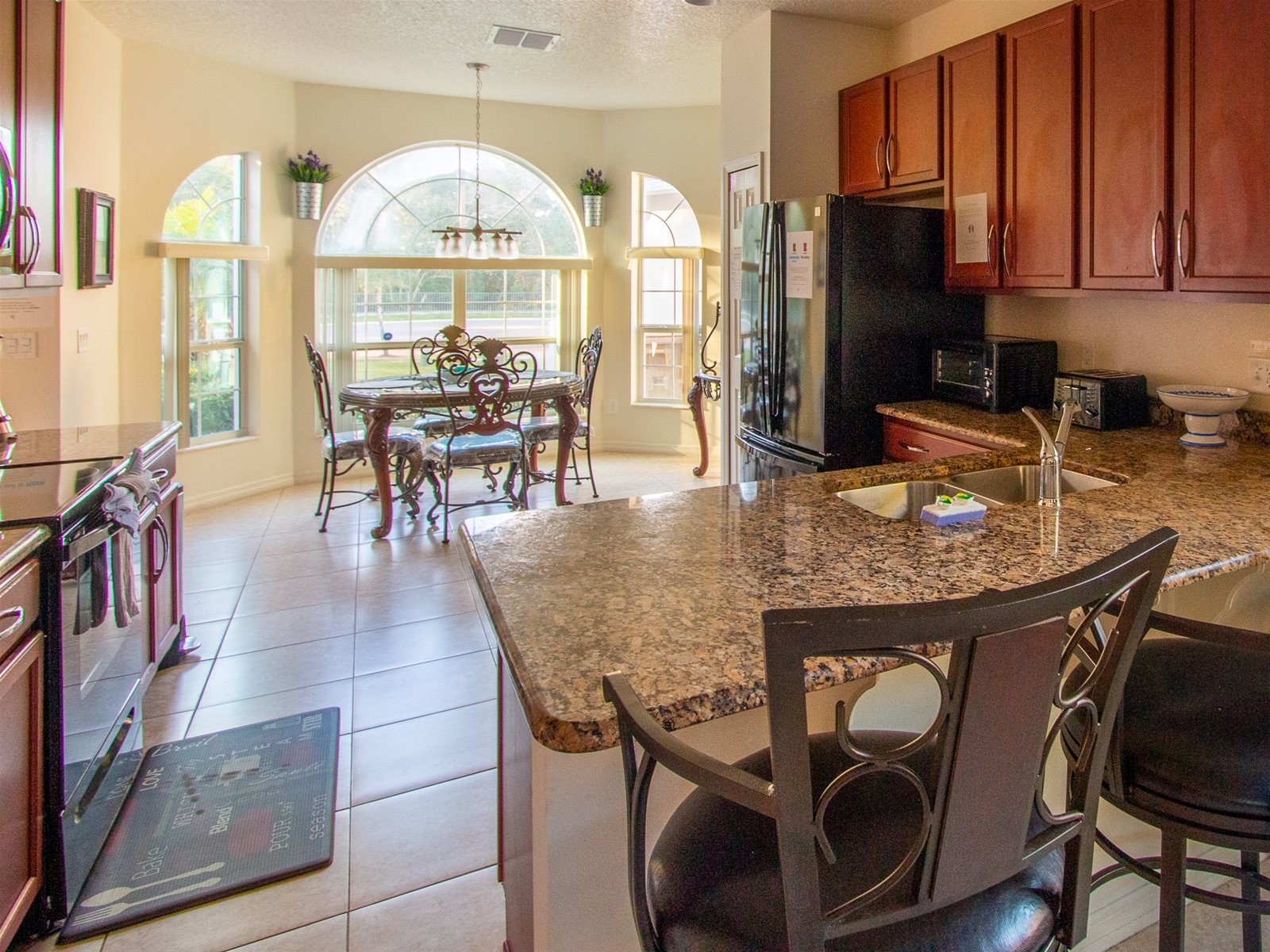 Fully stocked kitchen with granite countertops, stainless steel appliances, breakfast bar, and breakfast nook.