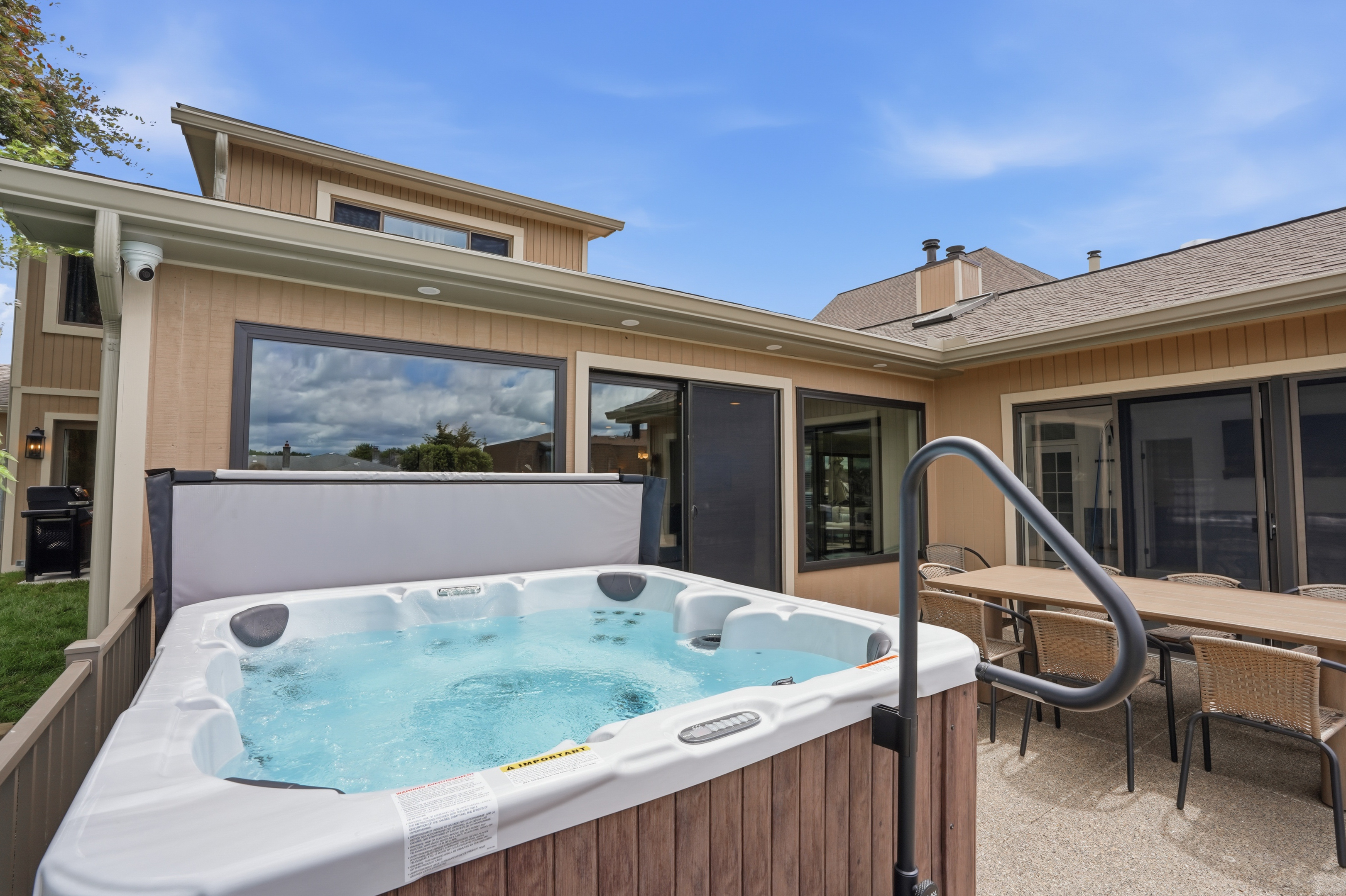 Unwind in the private outdoor hot tub surrounded by a spacious deck, dining area, and serene backyard setting—perfect for relaxing evenings.