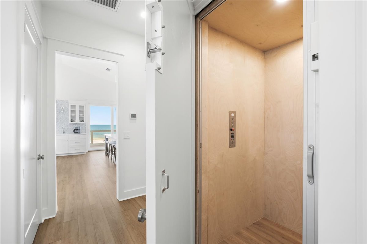 The elevator or the stairs can take you to the top floor of the house, which features vaulted ceilings, the main kitchen and living room, a king bedroom, and the primary suite.