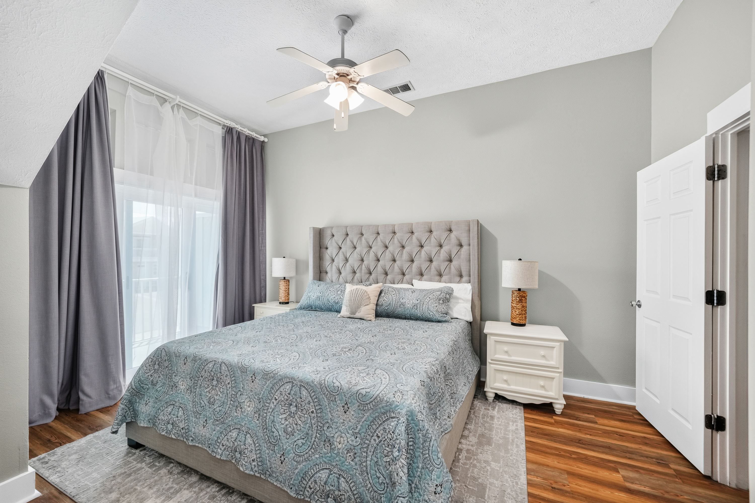 Bedroom 2: King-size bed, premium linens, ceiling fan, dresser, bedside lamp, spacious closet, and a bright private balcony, perfect for a relaxing stay.