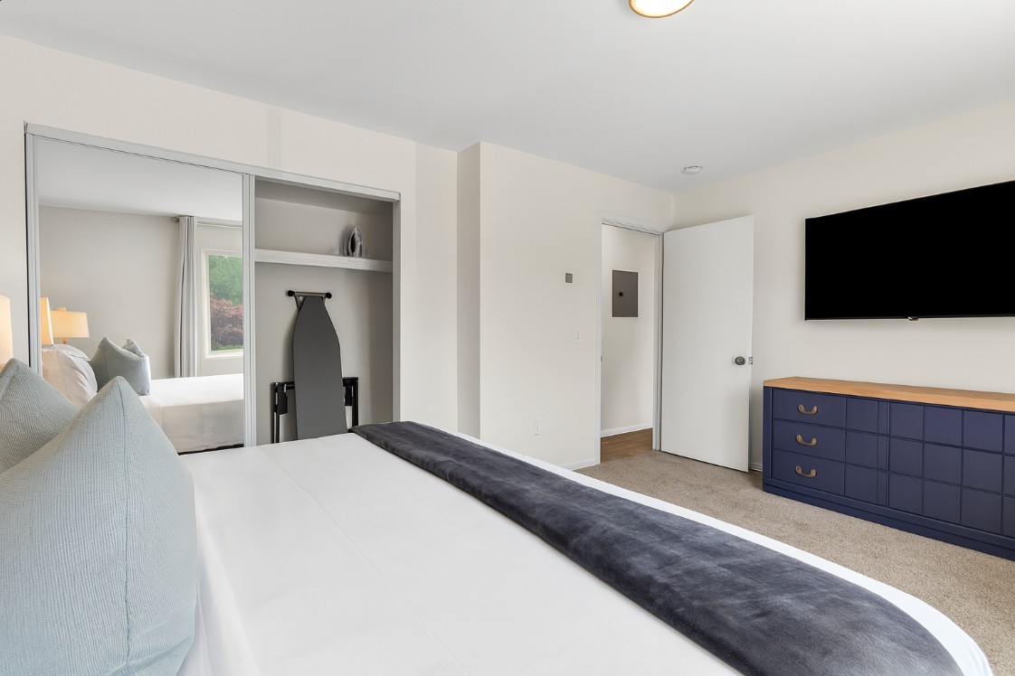 Spacious bedroom with Smart TV, dresser, and plenty of natural light for your comfort.