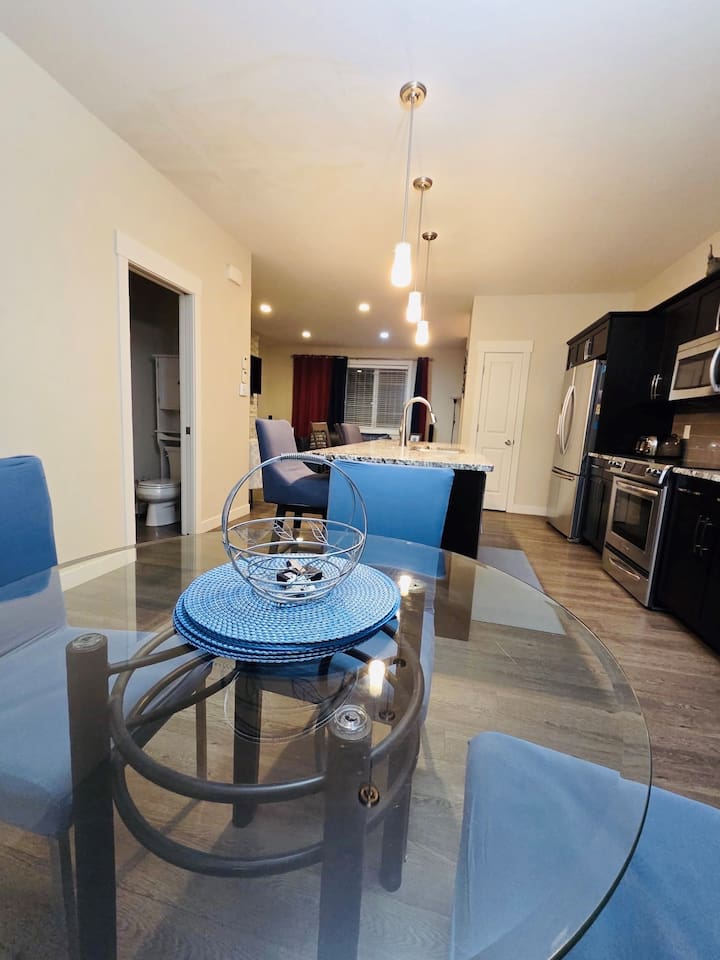 Sleek open kitchen with island seating, stainless appliances, chic dining.