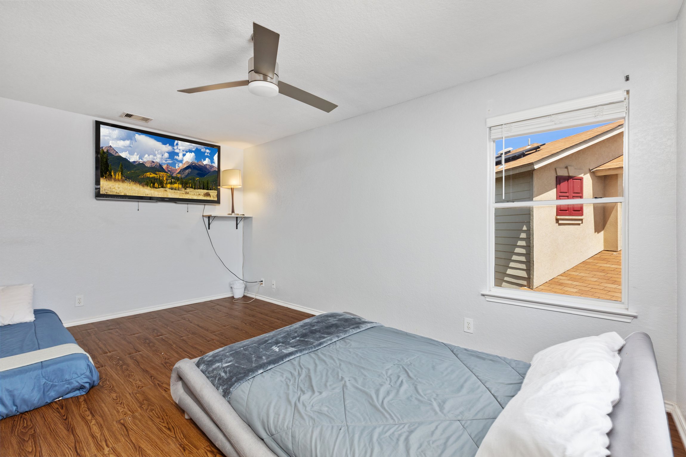 Queen and twin bedroom with wall-mounted Smart TV and streaming. Ceiling fan, room-darkening shades, and hotel-quality bedding. Current decorative blankets, bedding, and wall art are not shown in these photos.