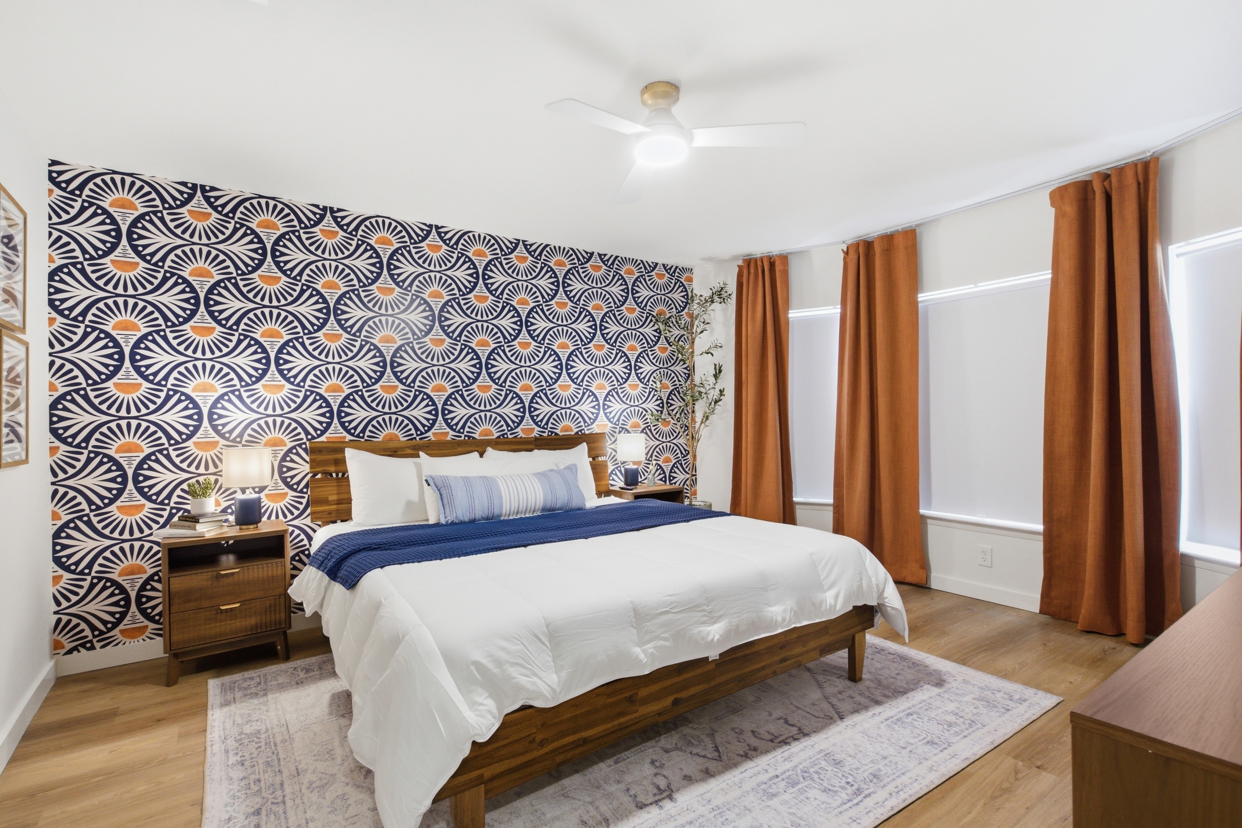 King Bed master suite with bold patterned accent wall, warm rust curtains, and Smart TV. Room-darkening shades and clothing storage included. 10-min walk to AT&T Stadium.