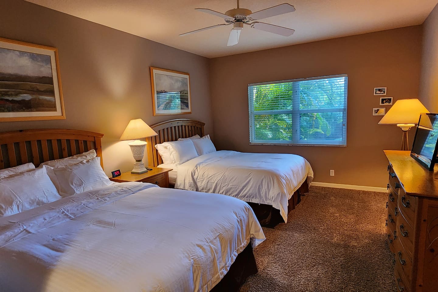 Comfortable bedroom with two beds, ceiling fan, dresser storage, and plenty of natural light.