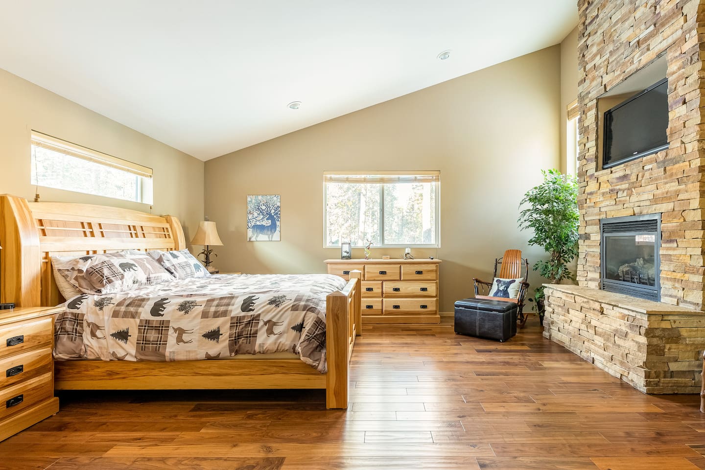 The spacious primary bedroom (the "Deer Den") on the main floor features a king-sized bed, a TV with Chromecast, a cozy gas fireplace, peaceful views, a large walk-in closet, a jacuzzi tub, and more!