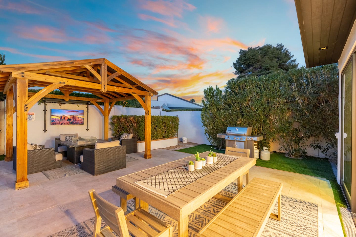 Under the glow of string lights and vivid skies, enjoy a backyard BBQ beside the wooden pergola and spacious dining table.