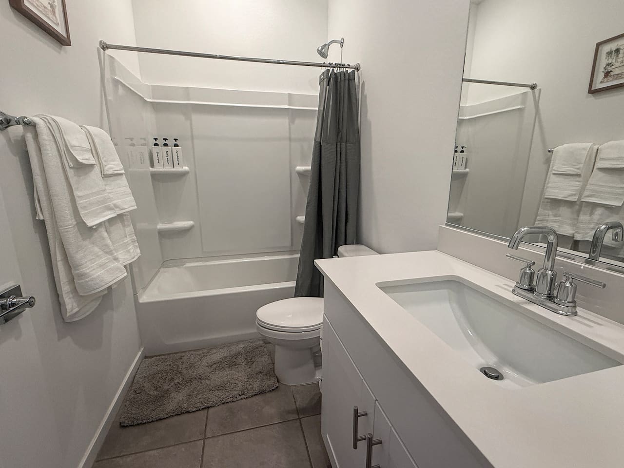 Bathroom with tub-shower, toilet, vanity, mirror, and towels