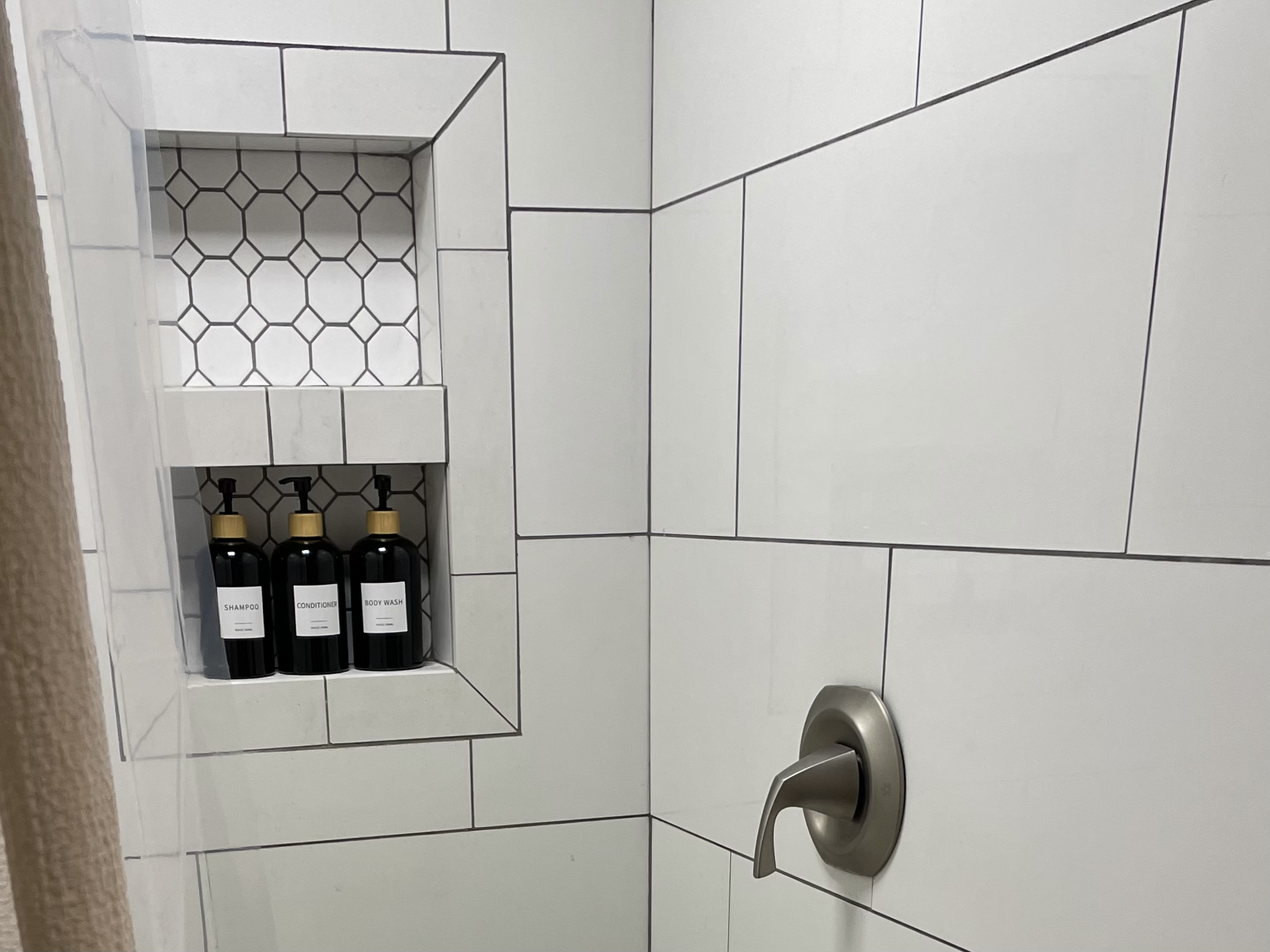 Walk-in tile shower with built-in niche and provided shampoo, conditioner, and body wash