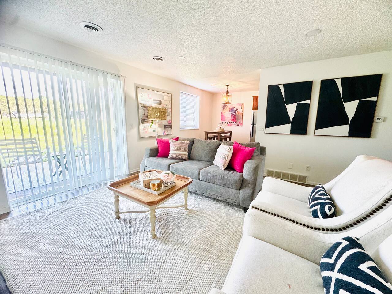 Bright and inviting living space with colorful floral decor, comfortable seating, and a playful area rug. Sliding glass doors open to scenic views, filling the room with natural light—perfect for morning coffee or evening unwinding.