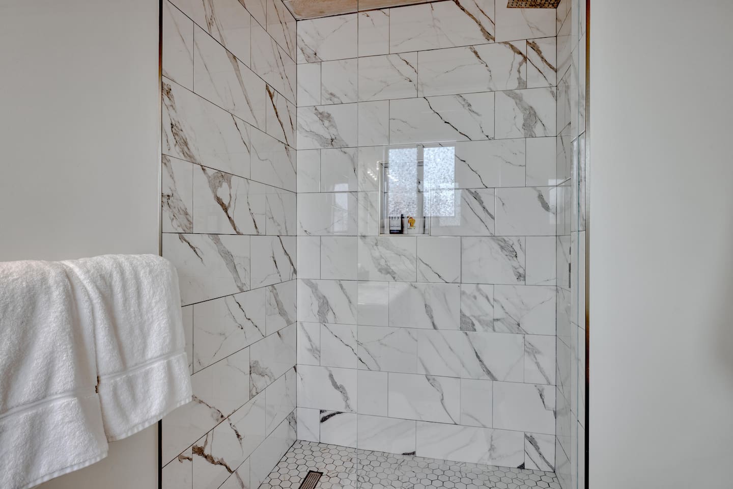 - Modern walk in shower with marble style tile walls for a sleek appearance  
- Built in niche keeps toiletries organized and easily within reach  
- Glass door enclosure creates an open feel while letting light flow freely  
