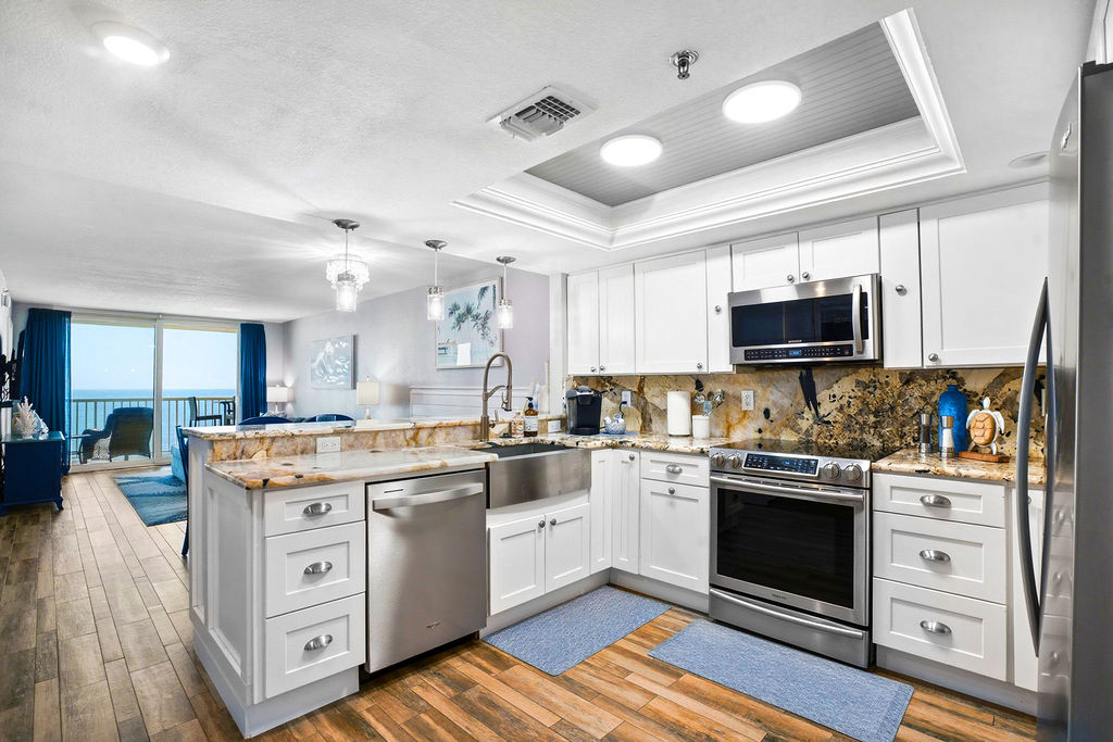 Open-concept gourmet kitchen in this beachfront vacation rental featuring stainless steel appliances, granite countertops, and ocean views from the living area.