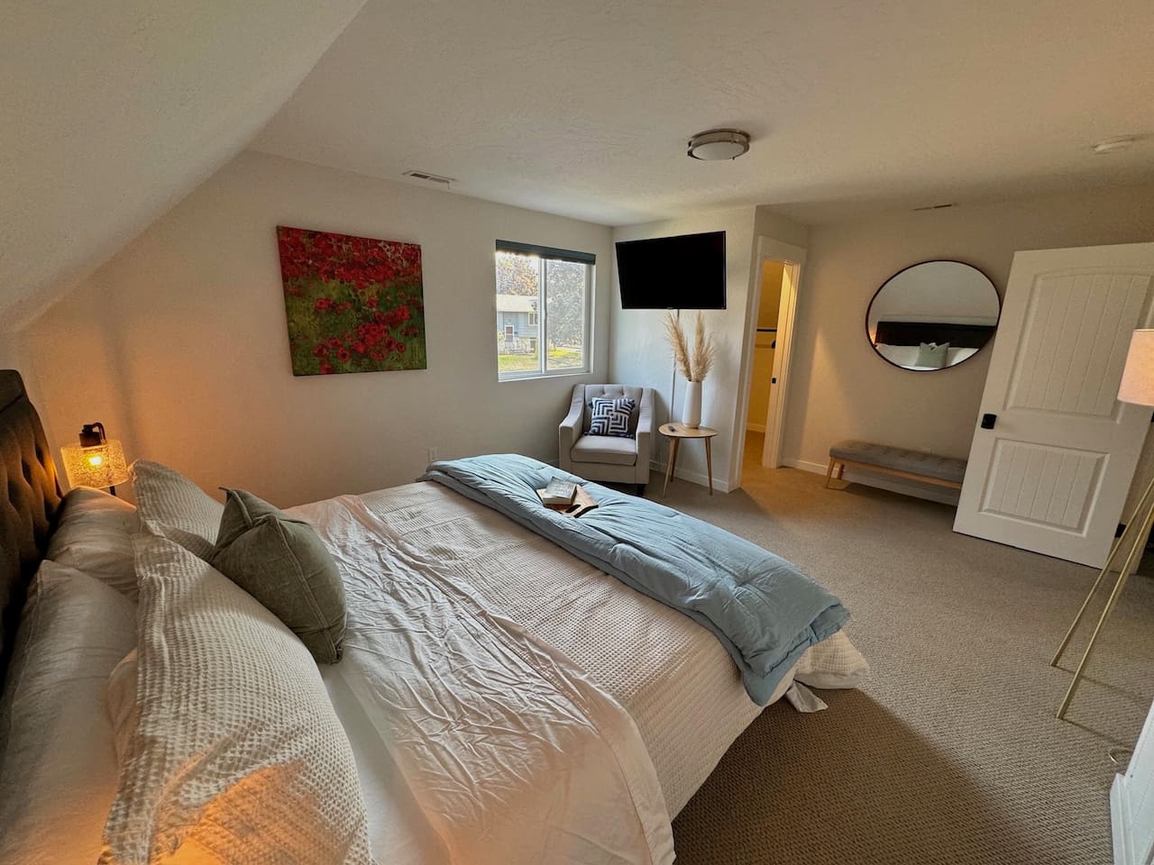 This primary bedroom features a king bed, black out shades, television, and a generous walk-in closet space. 