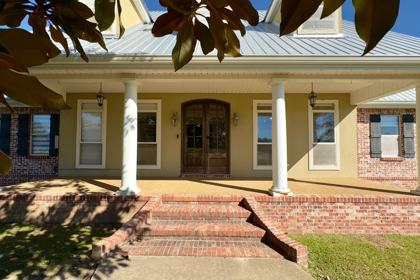 A concrete walkway guides guests through a landscaped approach, framed by tree branches for a picturesque arrival.