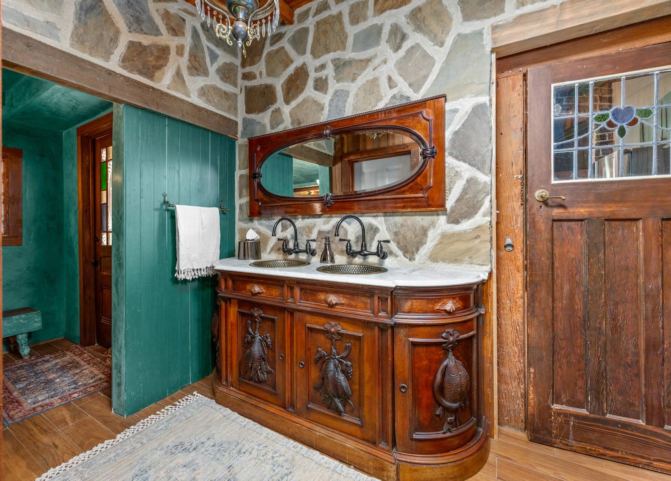 Even practical spaces deserve a little theater. In the Powder Room Annex, a 1920s dresser was transformed into a shared double vanity with handmade copper sinks. The stone walls add sound insulation, texture and a wonderful sense of permanence.