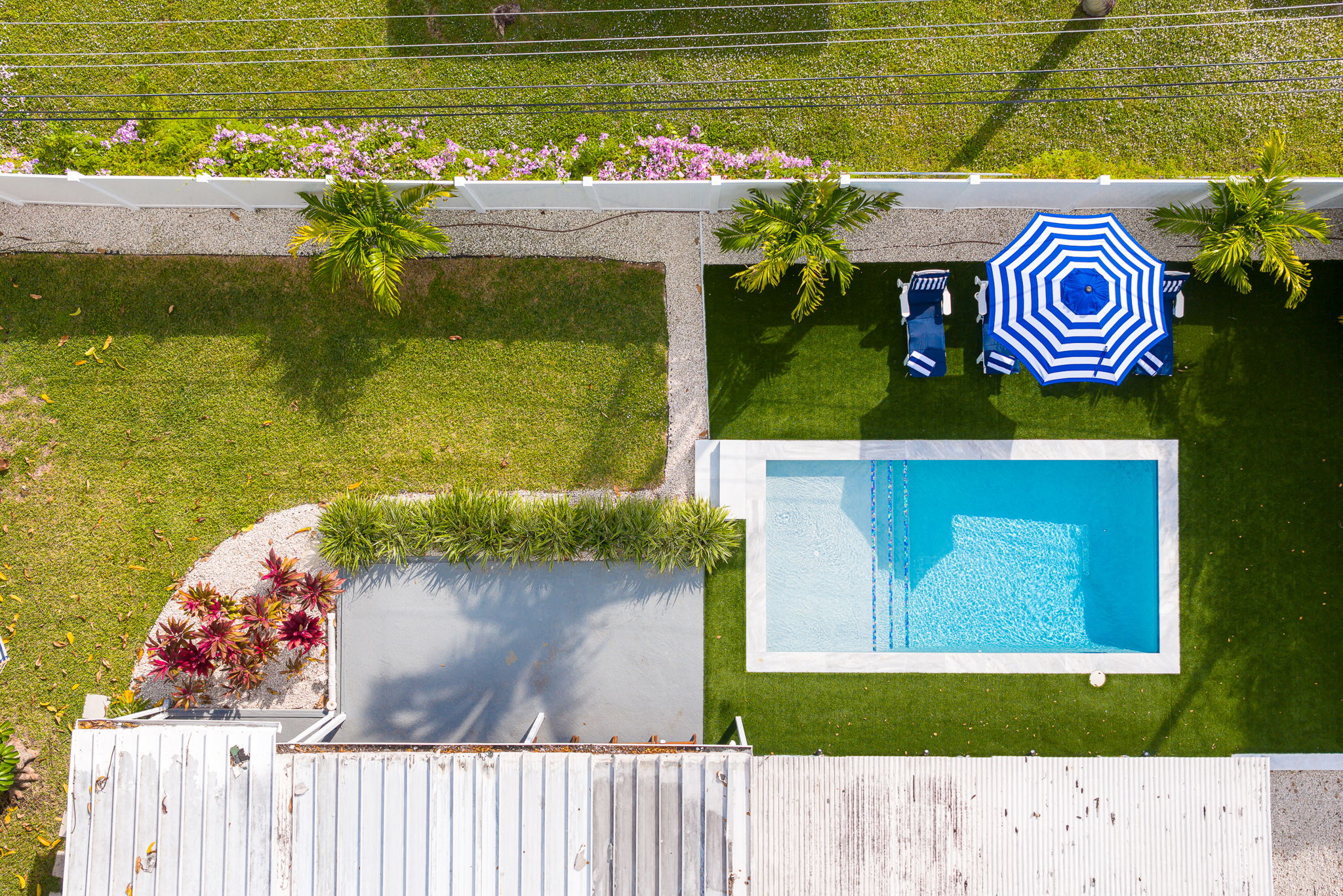 Soaring aerial perspectives highlight the home’s tranquil Pompano Beach neighborhood, private backyard oasis, covered carport, and extended driveway with space for 3 cars.