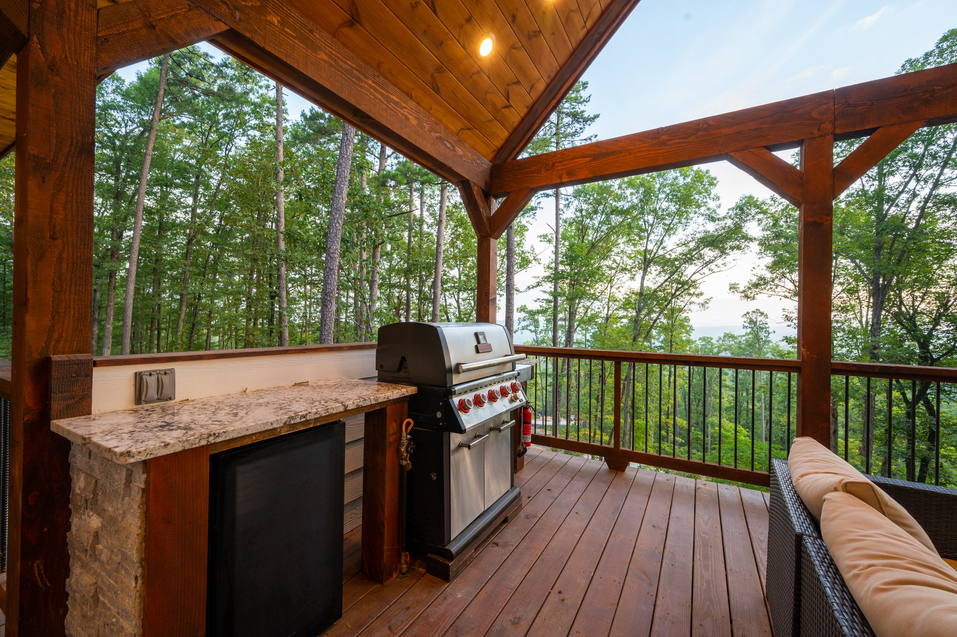 Outdoor grilling station with covered deck seating and forest surroundings