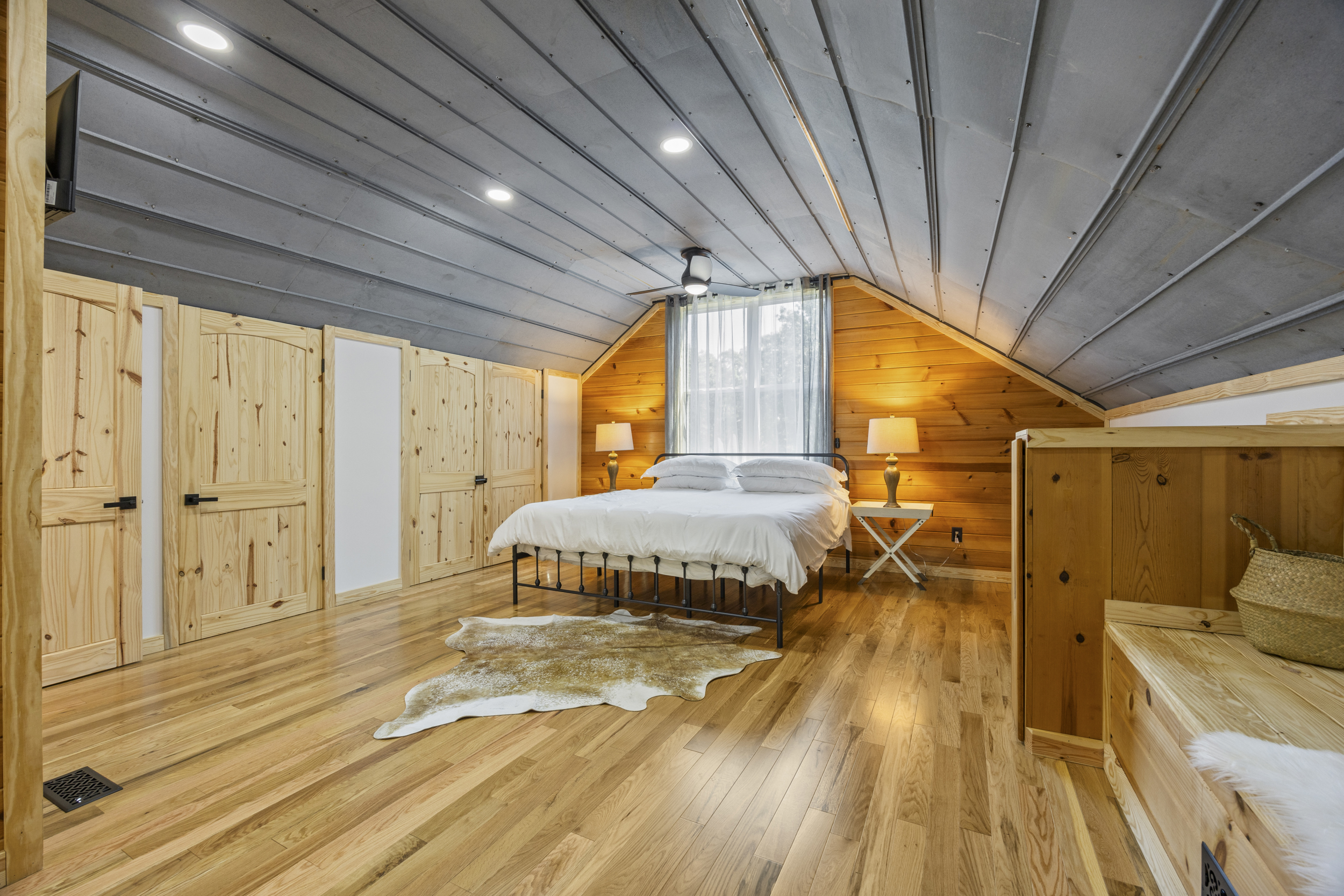 Spacious primary bedroom with king bed, vaulted ceilings, and warm wood accents.