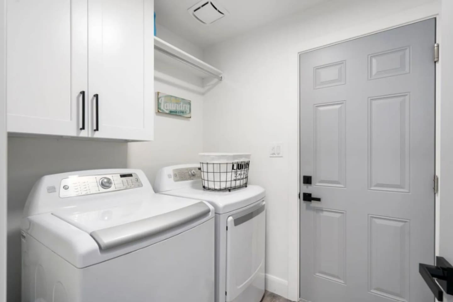 Modern laundry room with full-size washer and dryer, storage, and utility sink.