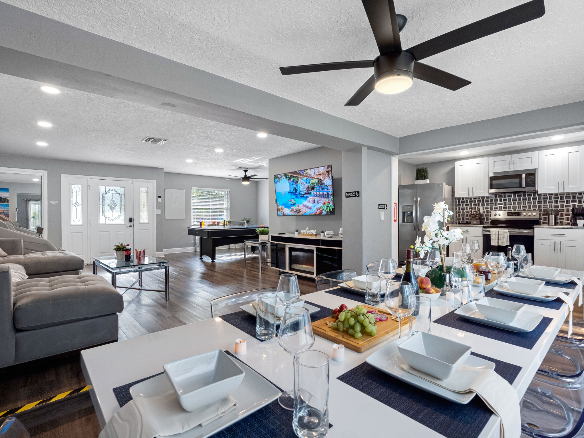 This sleek dining area features a modern white table with transparent chairs, perfect for large groups to gather and enjoy meals in style.