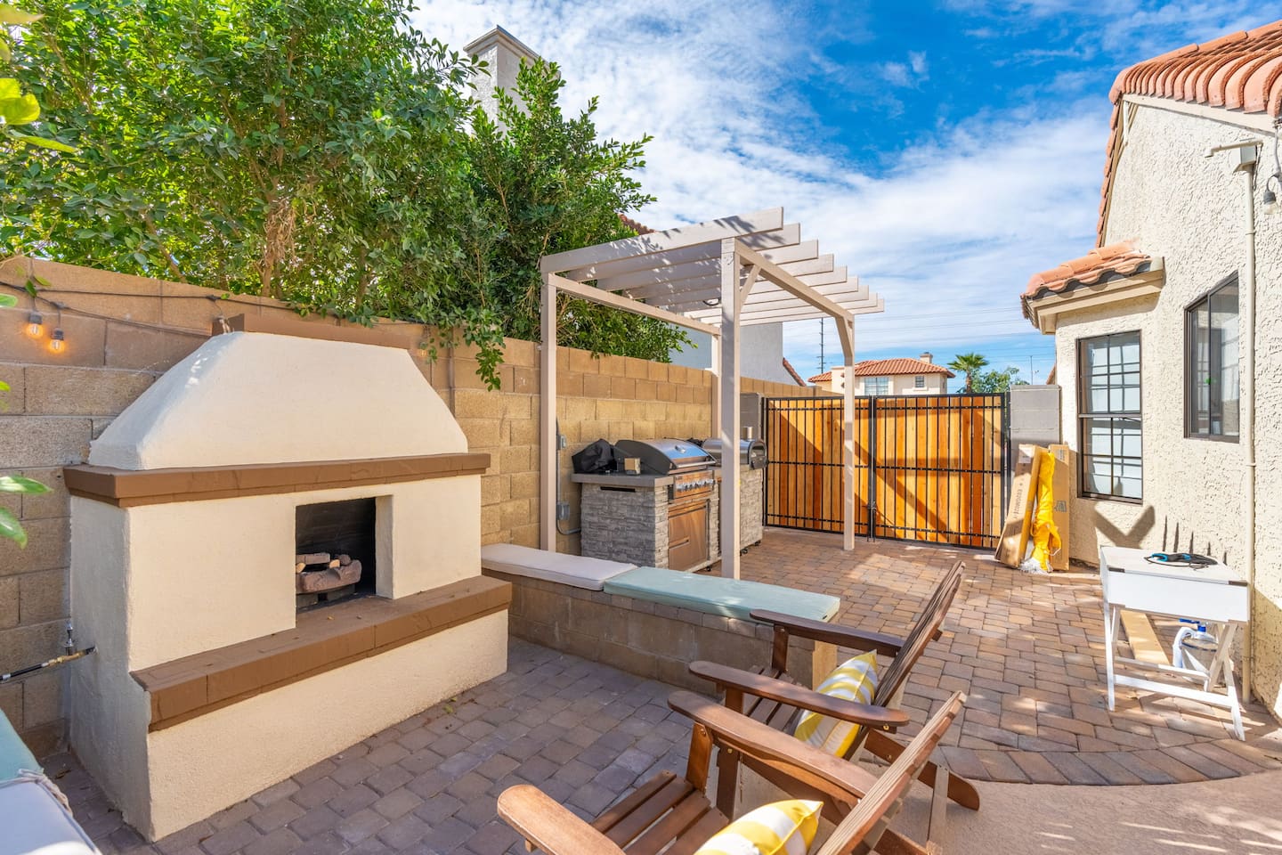 Multi-zone backyard with fireplace, pergola kitchen, loungers, and valley views—complete outdoor living and entertaining space.