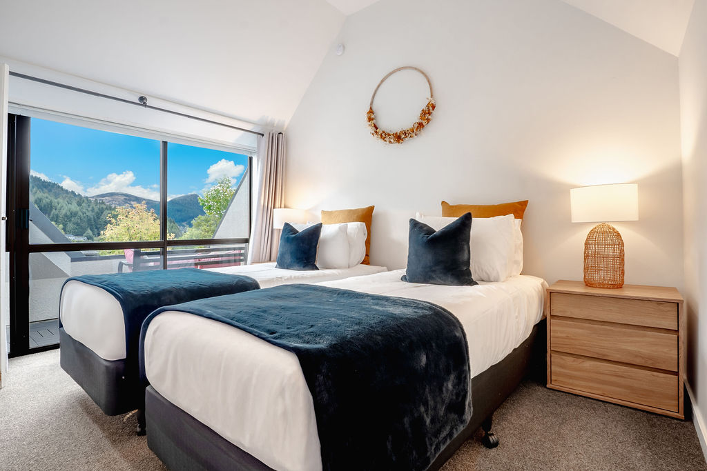 This upstairs bedroom can be set as king singles, with bedside storage, warm lighting and direct access to the balcony.