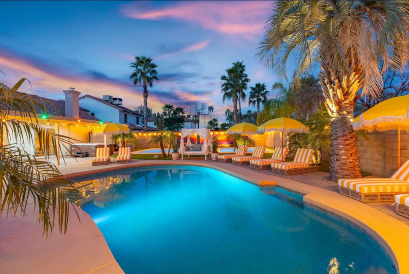 Twilight hues wash over the pool and loungers, framed by the softly lit home.