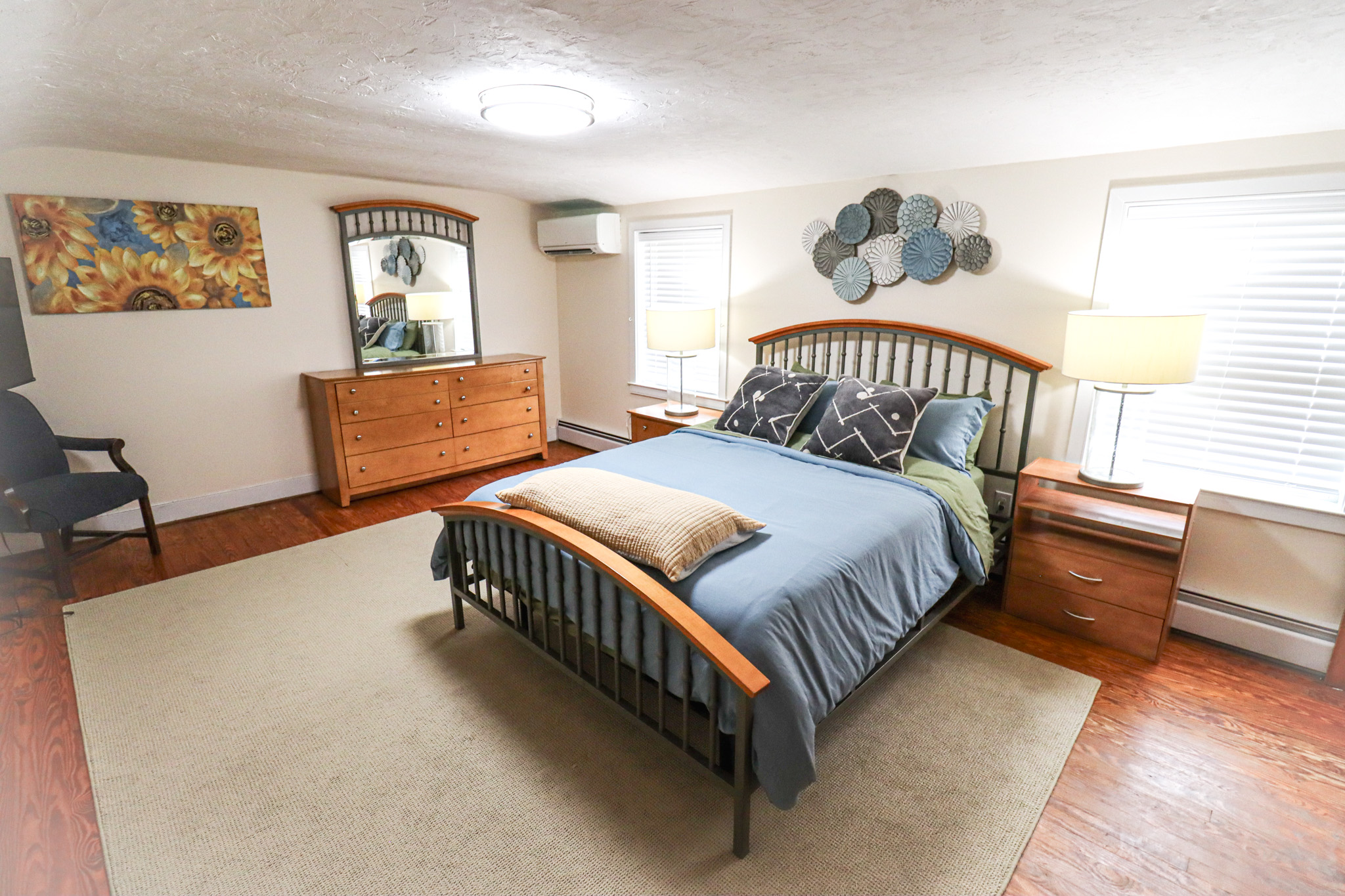 Relax in this bright and spacious bedroom featuring a comfortable queen bed, warm wood furnishings, and plenty of natural light