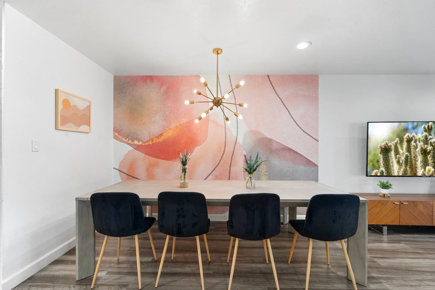 Sleek black chairs, a warm-toned mural, and natural wood textures offer a blend of comfort and curated style.

