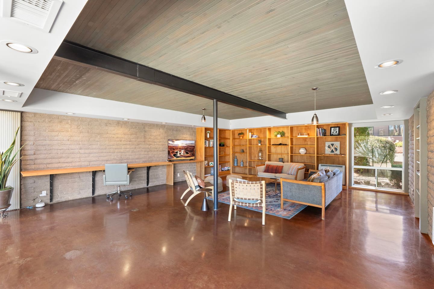 Expansive living space with built-in shelving, workspace, and warm modern design.