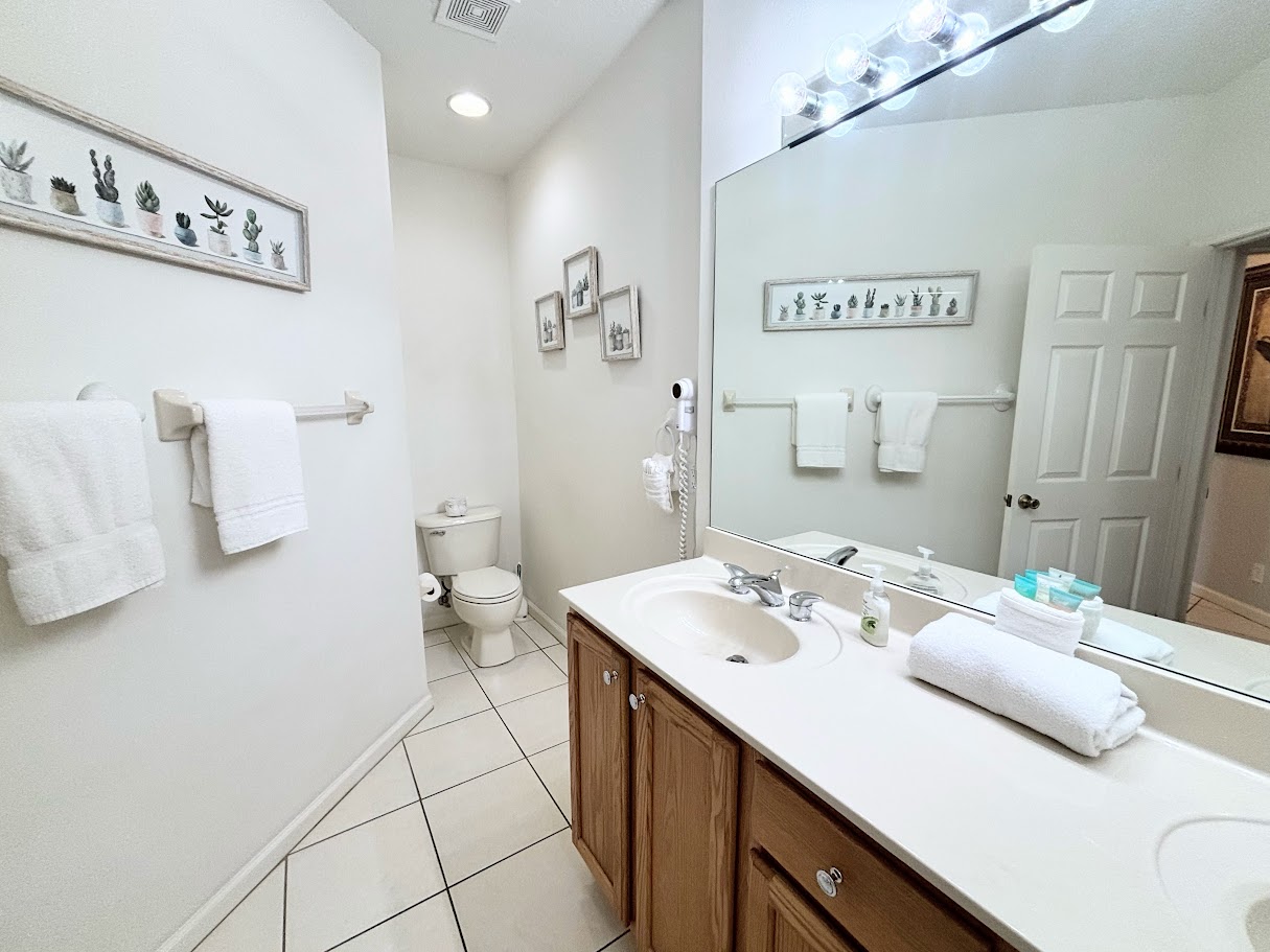 Spacious bathroom with a large vanity, full mirror, tile flooring, and plenty of counter space.