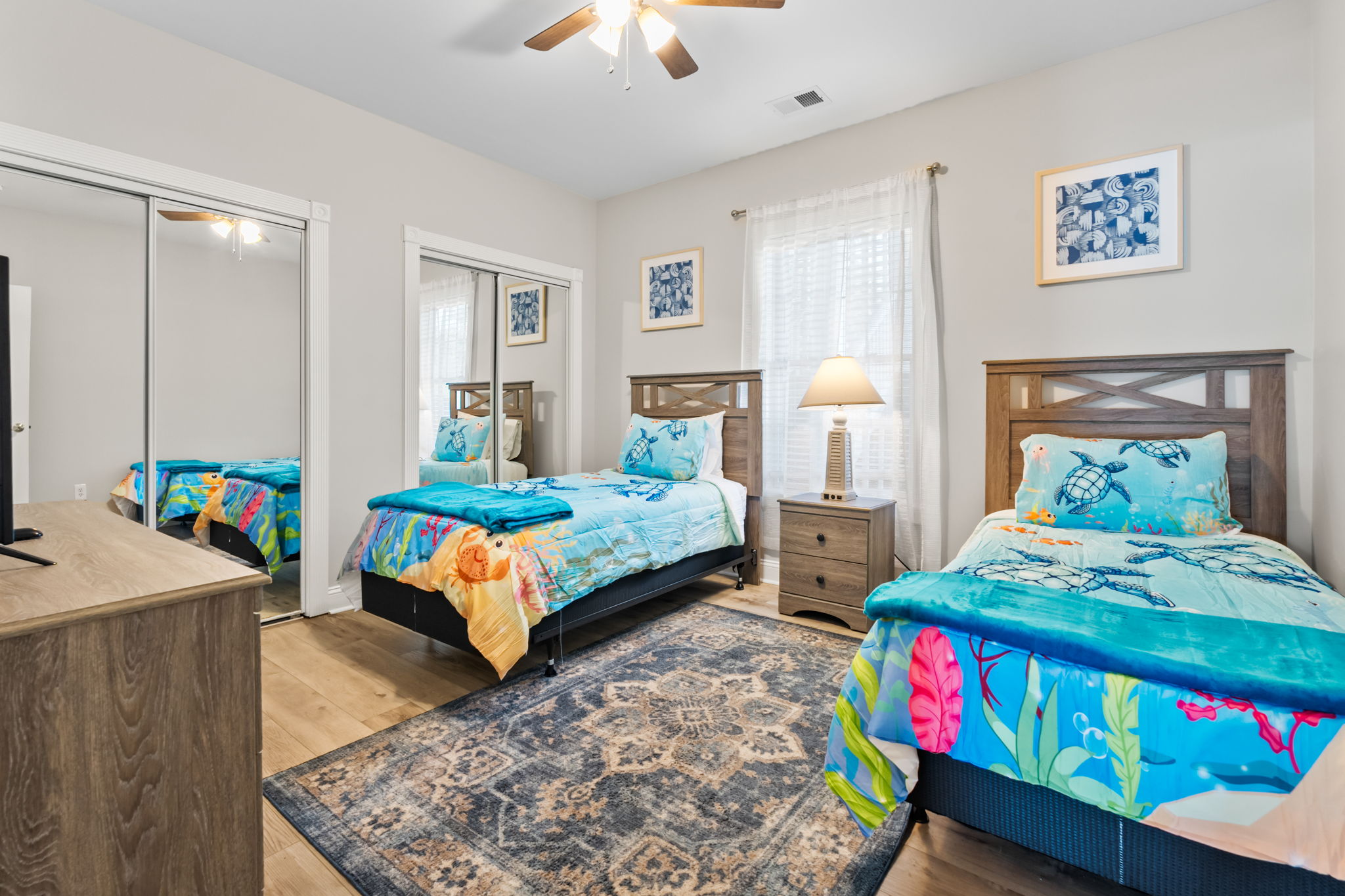 A cozy room featuring twin beds, a flat-screen TV, decorative mirror accents—creating a comfortable and inviting space to relax and unwind