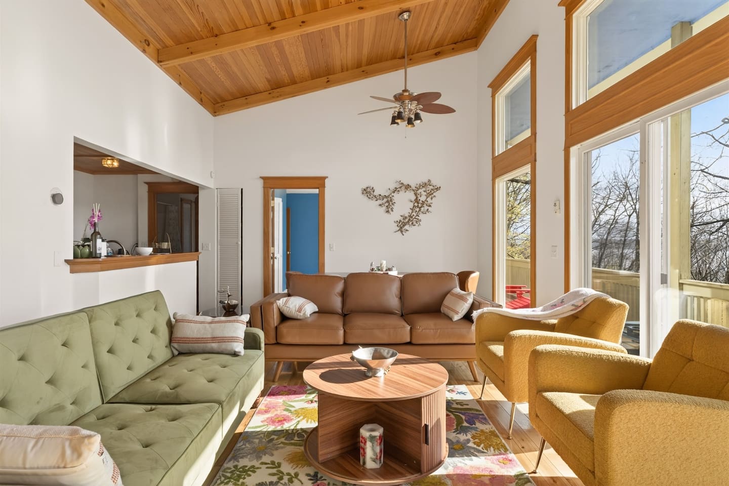 Sun-filled living room with soaring ceilings, warm wood accents, and floor-to-ceiling windows overlooking Canandaigua Lake—enjoy cozy seating, natural light, and seamless access to the balcony for relaxing mornings or peaceful evenings