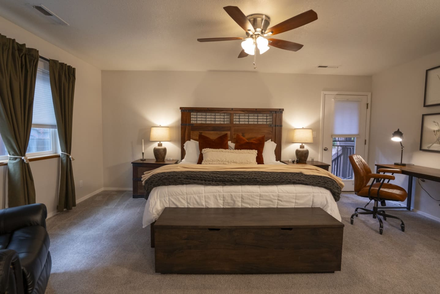 Spacious primary bedroom with a large king bed, work desk, closet storage, and comfortable seating.