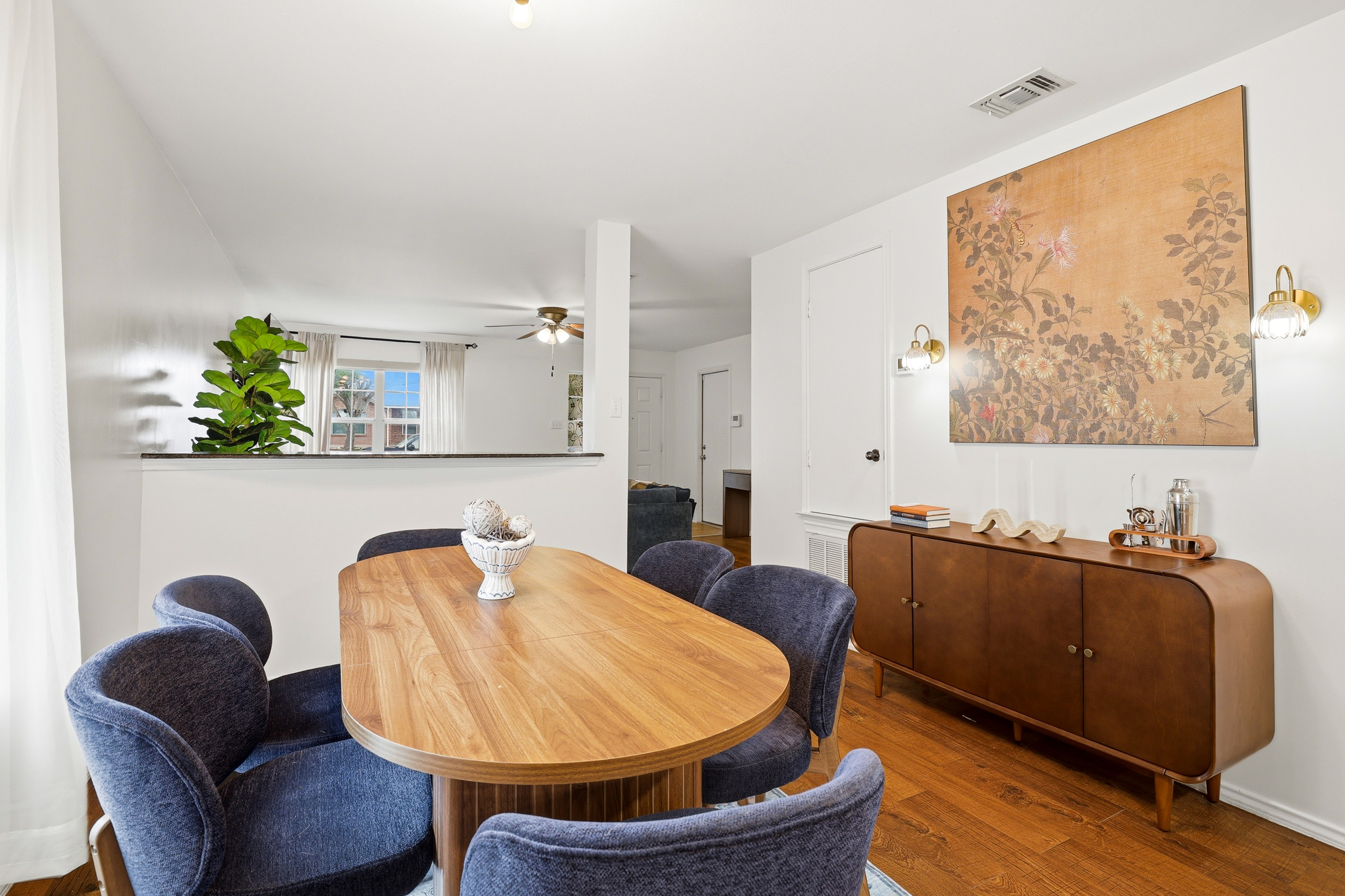 Dining table for 6 with modern pendant lighting, hardwood floors, and open sightlines to the kitchen and backyard patio. Bright, airy space perfect for group meals before a day at SeaWorld or Six Flags.