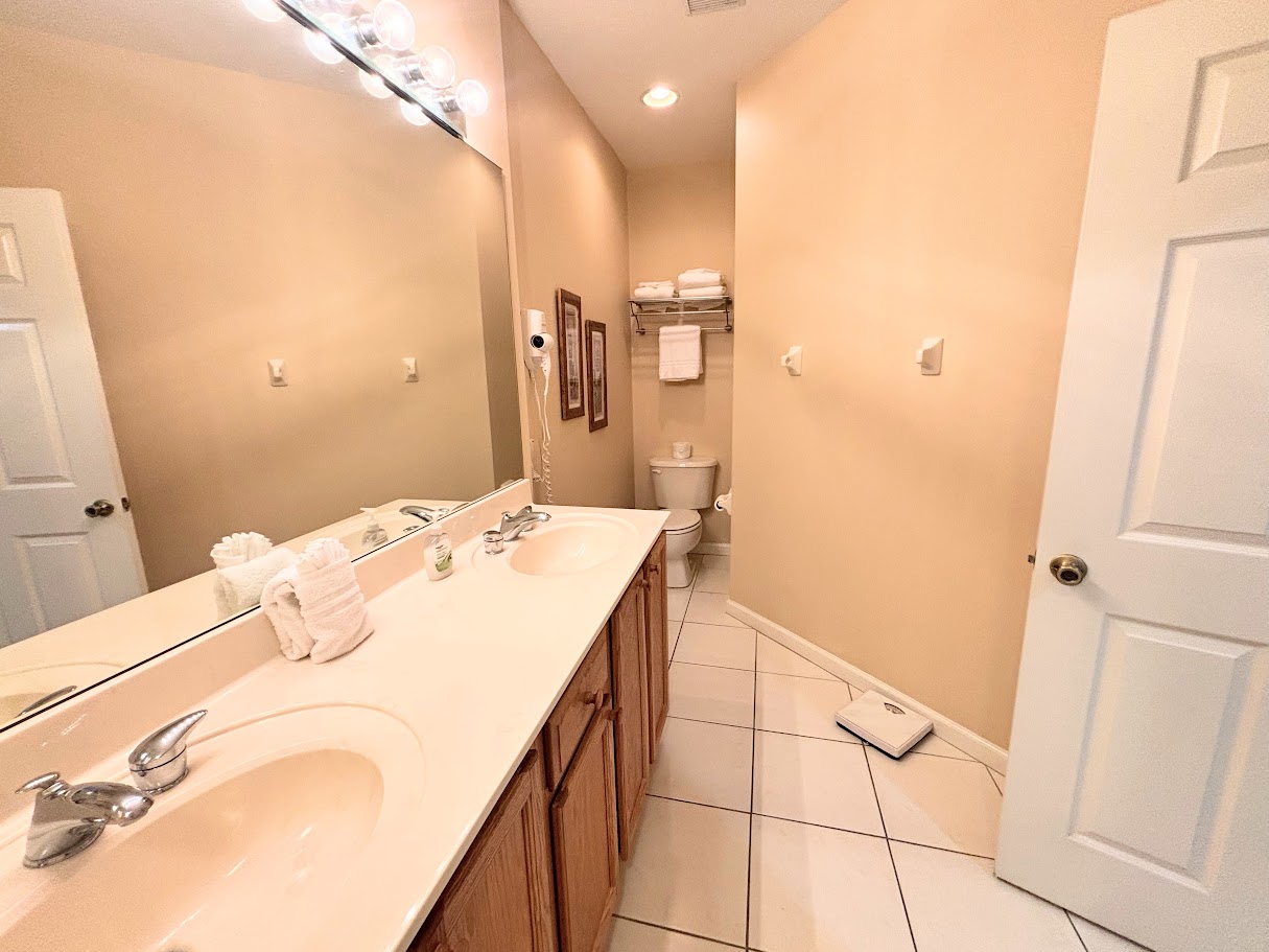 Clean and spacious bathroom featuring a large vanity, bright mirror lighting, tile flooring, and plenty of counter space.