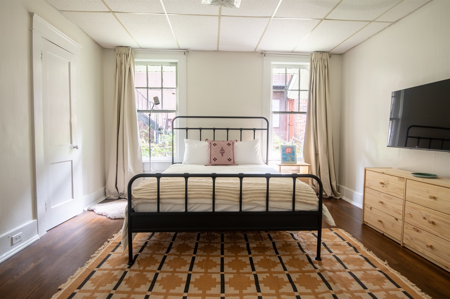 Spacious, light-filled bedroom with queen bed and smart TV for relaxation and comfort.