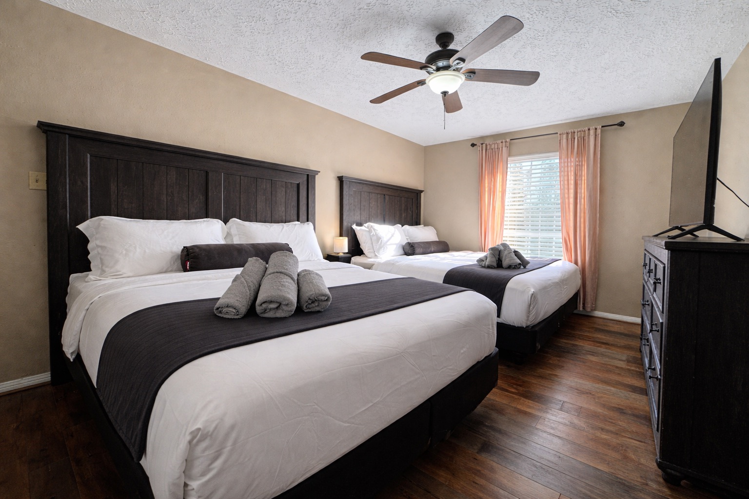 Spacious bedroom featuring a luxurious King bed and a comfortable Queen bed — perfect for families or couples traveling together. Enjoy premium bedding and unwind with your favorite shows on the 55” Smart TV.